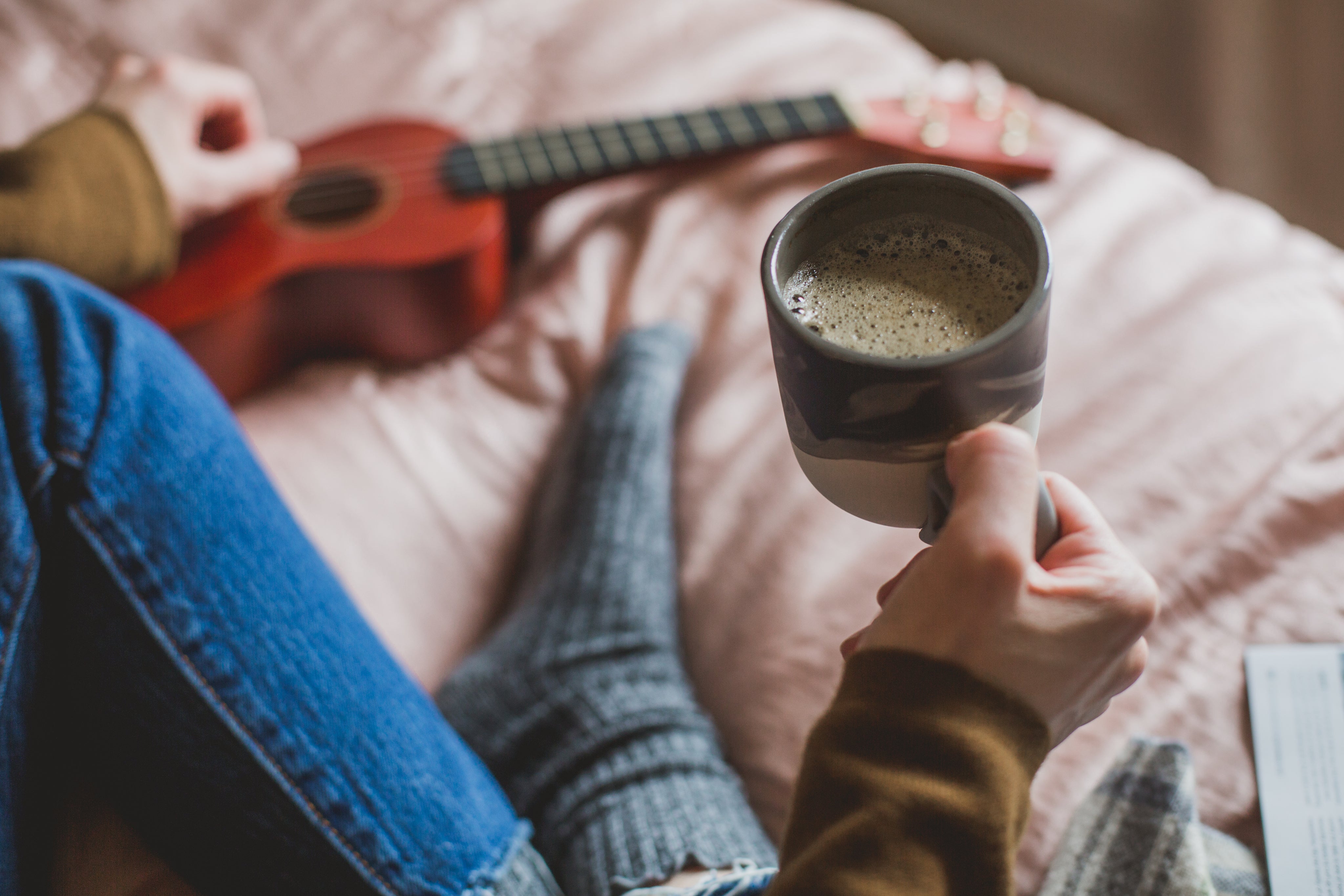 holding a coffee in bed